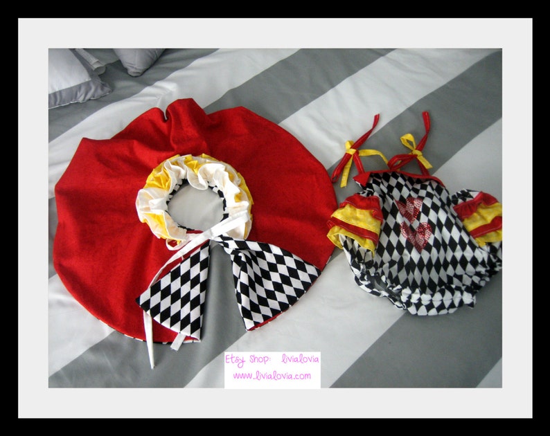 May include: A red and white checkered baby onesie with yellow trim and a red heart. The onesie is paired with a red cape with a white and black checkered trim.