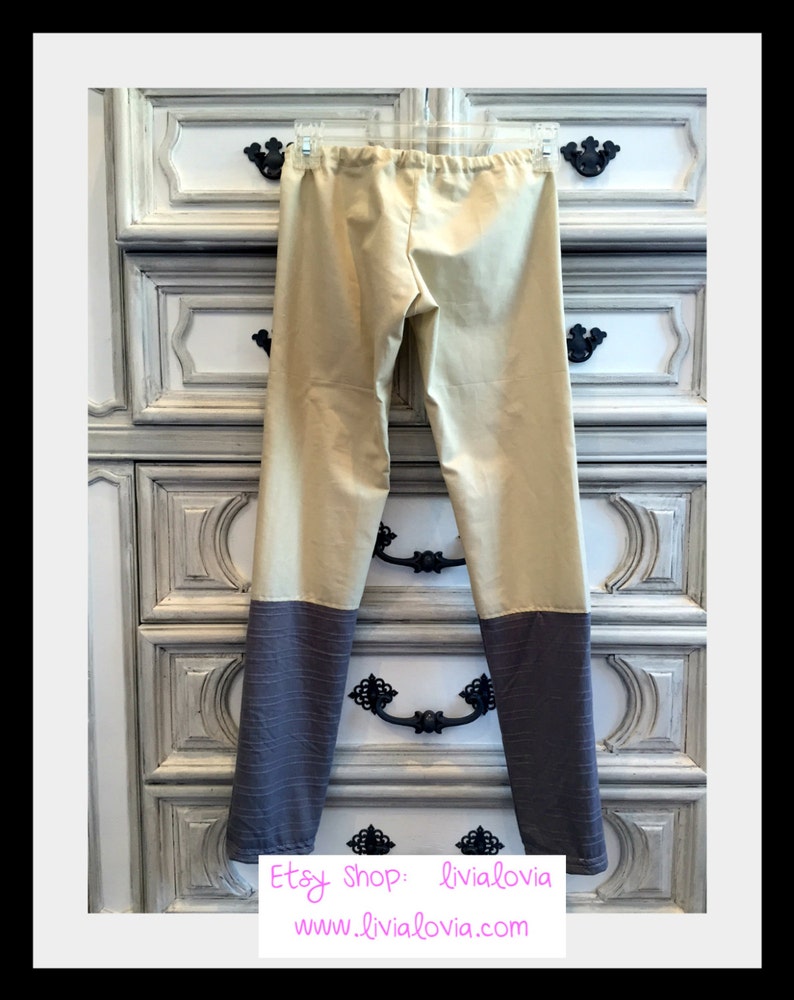 Op de afbeelding: Tweekleurige broek in beige en grijs, hangend aan een doorzichtige hanger. De broek heeft een beige bovenstuk en een grijs, getextureerd onderstuk. De elastische tailleband is zichtbaar. De Etsy shopnaam en website staan in de onderste hoek.