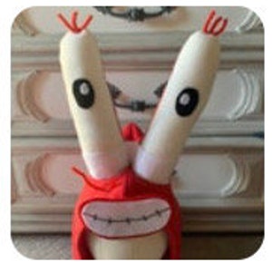May include: Red and white plush toy with long, white arms and a wide, toothy grin. The toy is shaped like a cartoon crab.