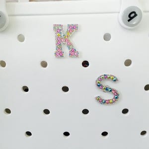 May include: White tote bag with a K and S monogram made of colorful rhinestones.