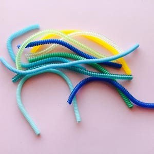 May include: A collection of colorful, coiled plastic cord organizers in blue, green, and yellow.