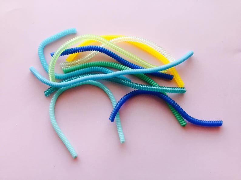 May include: A collection of colorful, coiled plastic cord organizers in blue, green, and yellow.