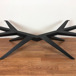 May include: Black metal table base with a unique, geometric design. The base has six legs that extend outward from a central point.