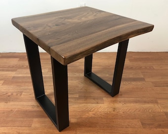 May include: Square wooden side table with a natural wood grain top and black metal legs. The table is approximately 24 inches wide and 24 inches long, with a height of 20 inches.
