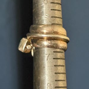 Peut inclure: Une bague en or avec une pierre de forme carr&eacute;e sertie dans la bande. La bague est mesur&eacute;e sur un calibreur de bague en m&eacute;tal, indiquant une taille 7.