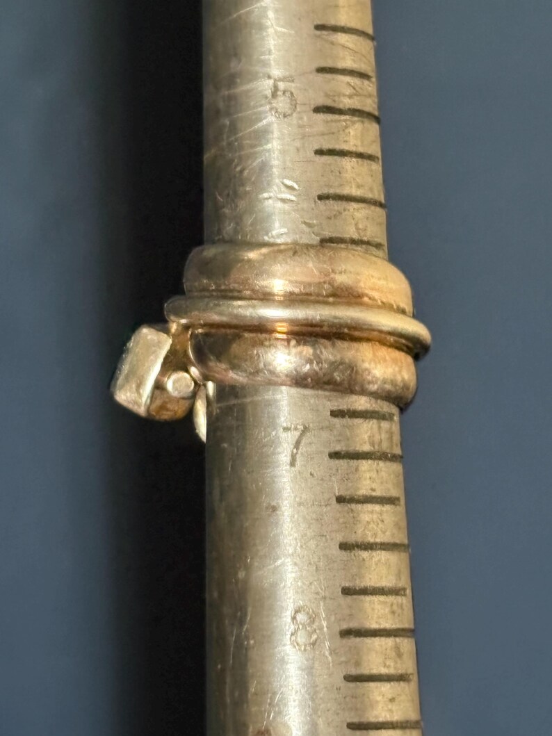 Peut inclure: Une bague en or avec une pierre de forme carr&eacute;e sertie dans la bande. La bague est mesur&eacute;e sur un calibreur de bague en m&eacute;tal, indiquant une taille 7.