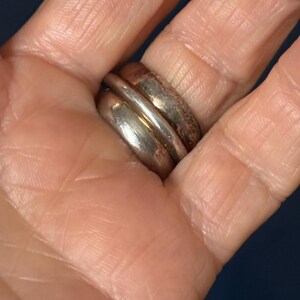 Peut inclure: Une bague en argent avec une large bande, pr&eacute;sentant un design &agrave; double couche. La bague est port&eacute;e &agrave; un doigt.
