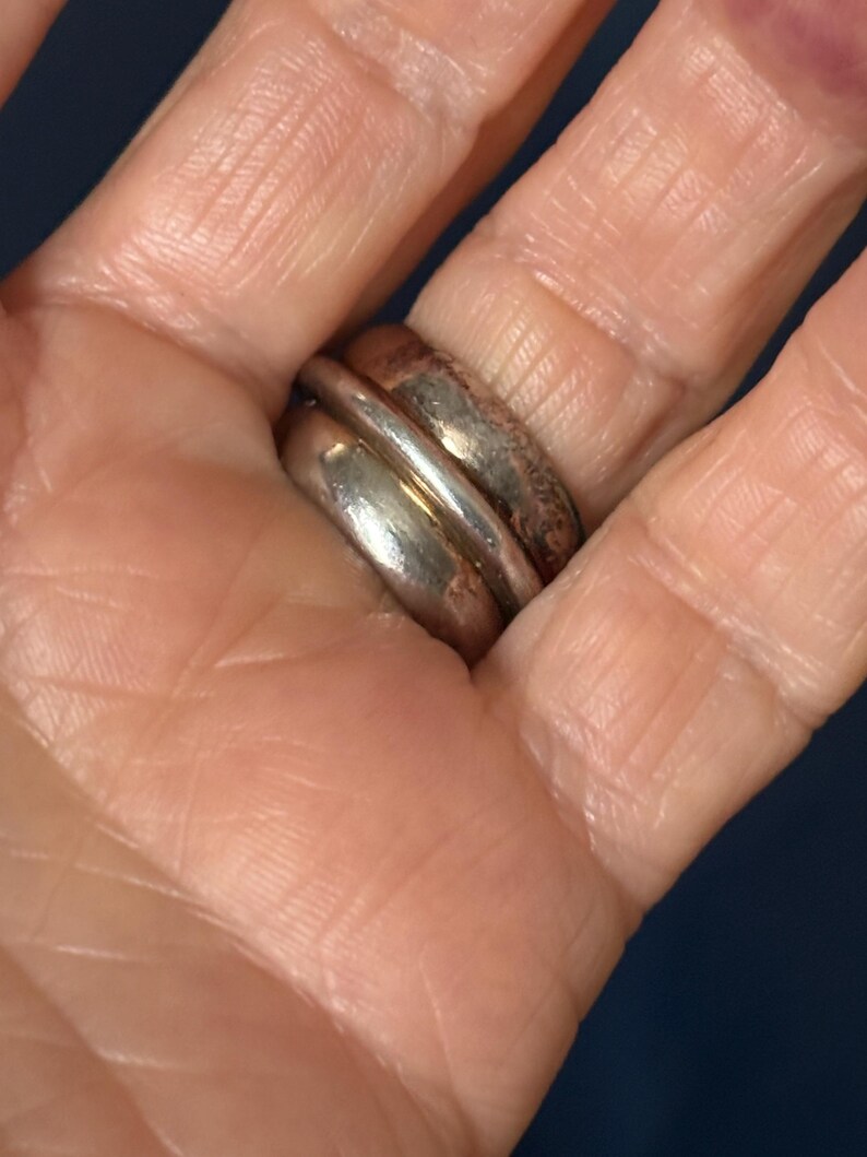 Peut inclure: Une bague en argent avec une large bande, pr&eacute;sentant un design &agrave; double couche. La bague est port&eacute;e &agrave; un doigt.