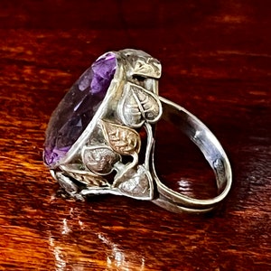 May include: A silver ring with an amethyst gemstone set in a leaf design.