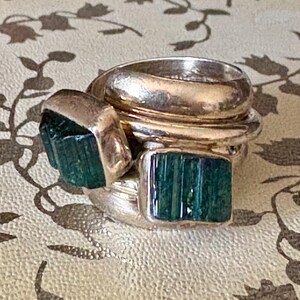 Peut inclure: Une bague en argent avec plusieurs bandes et deux pierres pr&eacute;cieuses vertes.