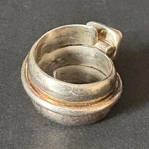 Peut inclure: Bague en argent avec un design unique et multicouche. La bague est compos&eacute;e de plusieurs bandes torsad&eacute;es et entrelac&eacute;es, cr&eacute;ant un aspect textur&eacute; et complexe.