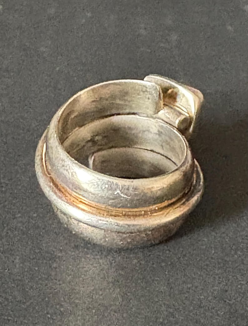Peut inclure: Bague en argent avec un design unique et multicouche. La bague est compos&eacute;e de plusieurs bandes torsad&eacute;es et entrelac&eacute;es, cr&eacute;ant un aspect textur&eacute; et complexe.