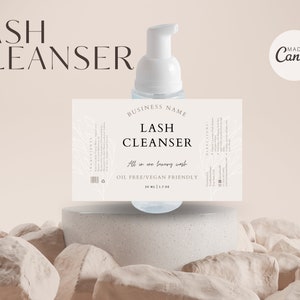 May include: A white lash cleanser bottle with a pump dispenser, labeled "LASH CLEANSER." The label includes "All in one luxury wash" and "OIL FREE/VEGAN FRIENDLY." The bottle is 1.7 fl oz (50 ml). The background is a neutral beige with a "Made in Canva" logo.