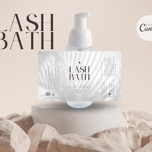 May include: A white bottle with a pump dispenser and a label that says "Lash Bath Oil Free Vegan Friendly 200 ml". The bottle is sitting on a white rock-like surface.