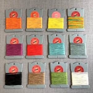 May include: Twelve spools of waxed linen thread in various colors, including orange, yellow, red, green, blue, black, and white. Each spool is labeled with "Jacks Stitchery" and "Soles & Soles".