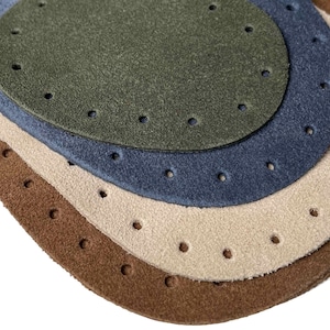 May include: Four round leather patches in different sizes and colours: brown, beige, blue, and green. Each patch has a circle of evenly spaced holes around the edge.