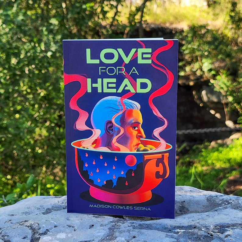 Puede incluir: Una portada de libro con fondo azul y el t&iacute;tulo "LOVE FOR A HEAD" en letras verdes y rojas. La portada presenta una cabeza azul en un taz&oacute;n rojo con vapor saliendo del taz&oacute;n.