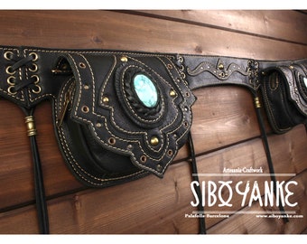 May include: Black leather belt with three attached pouches, each with a decorative design and a turquoise stone. The belt has a lace-up closure and is adorned with gold-toned accents. The pouches have a zipper closure and are perfect for carrying small items. The belt is labeled "Artesania Craftwork SIBO YANKE Palafolls-Barcelona www.siboyanke.com".