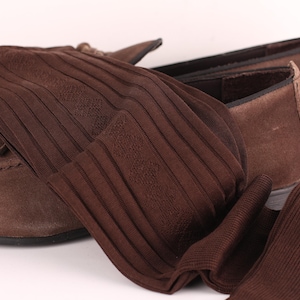 Peut inclure: Mocassins en daim marron avec une paire de chaussettes côtelées marron. Les chaussettes ont un motif subtil.