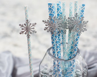 May include: A set of blue and white striped paper straws with silver glitter snowflake toppers in a clear glass vase filled with silver glitter.