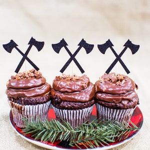 Pu&ograve; includere: Tre cupcake al cioccolato con glassa al cioccolato e noci tritate in cima. Ogni cupcake &egrave; sormontato da un topper a forma di ascia di carta nera.