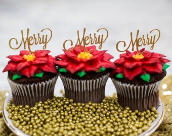May include: Three chocolate cupcakes decorated with red poinsettia frosting and topped with gold glitter "Merry" picks. The cupcakes are sitting on a white plate with gold sprinkles.