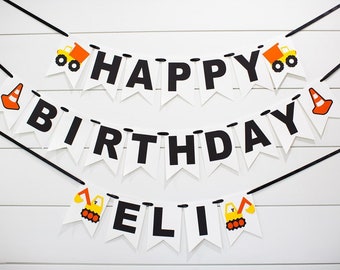 May include: A white and black construction themed banner with the words "Happy Birthday Eli" in black letters. The banner has yellow construction trucks and orange traffic cones.