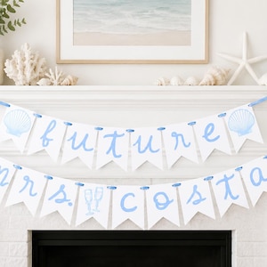 Op de afbeelding: Een tweelaagse witte vlaggenlijn met lichtblauwe letters die future mrs. costa spellen. De vlaggenlijn is versierd met lichtblauwe illustraties van schelpen en twee champagneglazen, alles aan elkaar geregen met een lichtblauw lint.