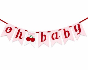 Op de afbeelding: Een decoratieve slinger met lichtroze vlaggetjes aan een rood koord. De letters vormen de tekst "oh baby" in een glinsterend rood lettertype. Een wit vlaggetje in het midden toont twee rode kersen met een klein lichtroze strikje.