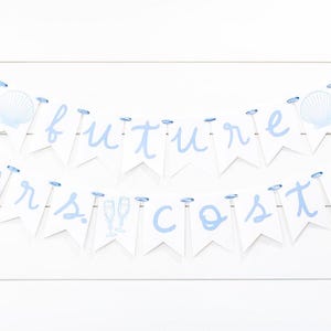 Op de afbeelding: Een decoratieve banner met twee lagen bestaande uit witte wimpels aan een lichtblauw lint. De bovenste rij spelt future met schelpenafbeeldingen en de onderste rij spelt mrs. costa met afbeeldingen van champagneglazen in lichtblauw.