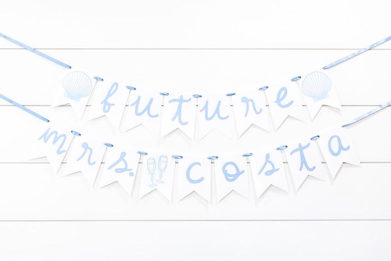 Op de afbeelding: Een decoratieve banner met twee lagen bestaande uit witte wimpels aan een lichtblauw lint. De bovenste rij spelt future met schelpenafbeeldingen en de onderste rij spelt mrs. costa met afbeeldingen van champagneglazen in lichtblauw.