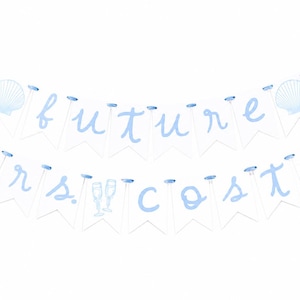 Op de afbeelding: Een tweelaagse slinger met witte vlaggetjes en lichtblauwe letters die de tekst future mrs. costa vormen. De slinger is voorzien van een lichtblauw lint, twee afbeeldingen van schelpen bovenaan en twee champagneglazen in het midden.