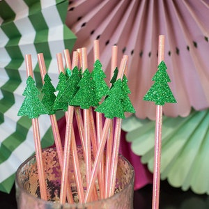 May include: A bunch of pink and white striped paper straws with green glitter Christmas tree toppers. The straws are in a clear glass jar.