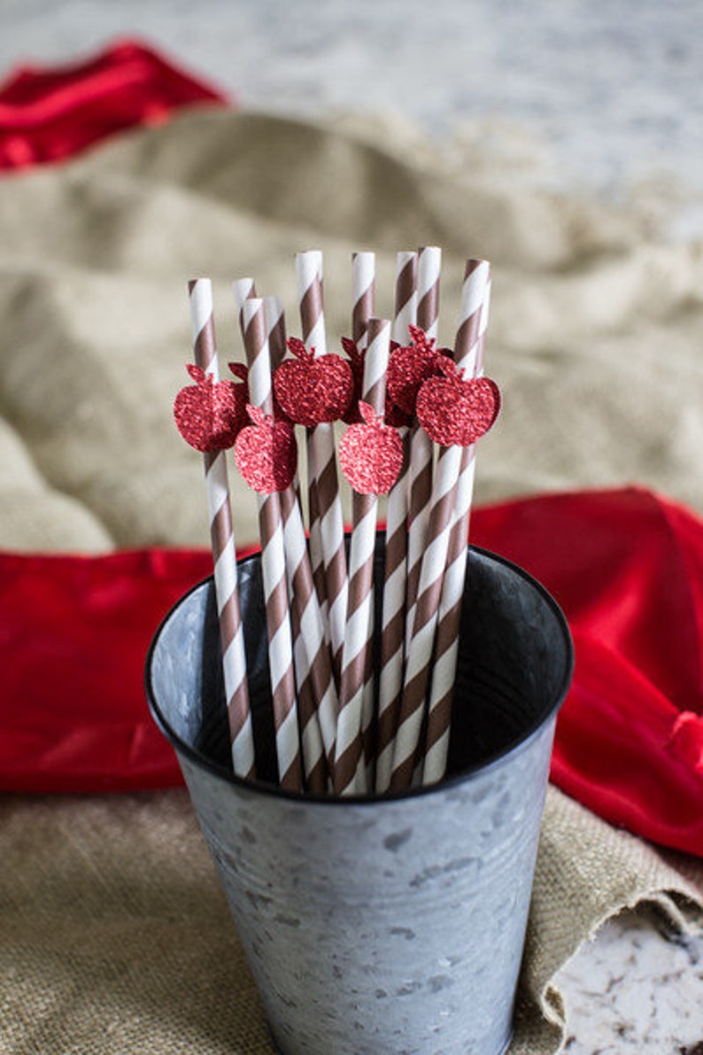 May include: A metal bucket filled with brown and white striped paper straws with red glitter apple toppers.