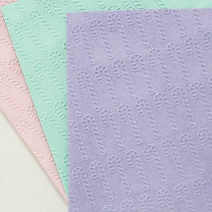 May include: Three sheets of paper with a candy cane pattern. The sheets are pink, light blue, and lavender.