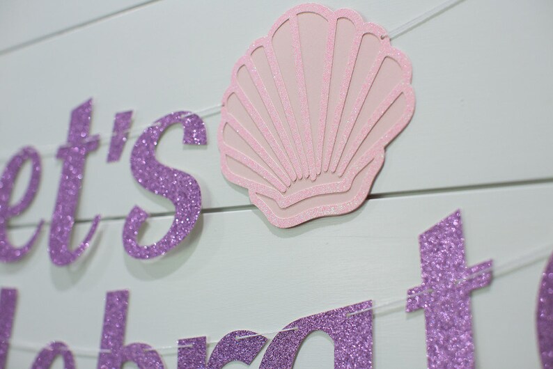 May include: Purple glitter banner with the text "Let's Celebrate" and a pink glitter seashell.