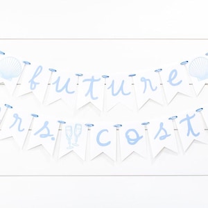 Op de afbeelding: Een decoratieve banner met twee lagen bestaande uit witte wimpels aan een lichtblauw lint. De bovenste rij spelt future met schelpenafbeeldingen en de onderste rij spelt mrs. costa met afbeeldingen van champagneglazen in lichtblauw.