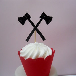 Pu&ograve; includere: Un cupcake rosso con glassa bianca sormontato da due topper per cupcake a forma di ascia di carta nera.