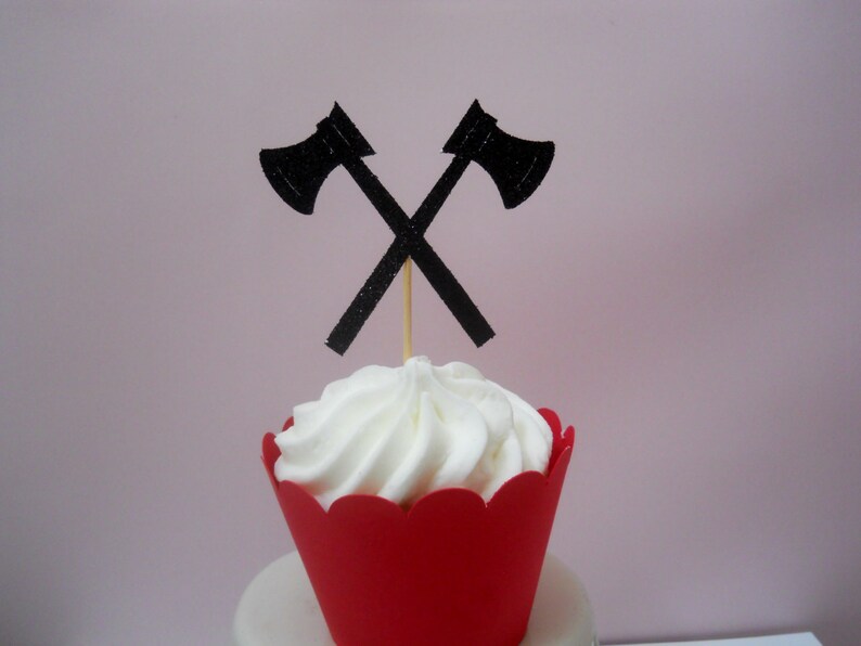 Pu&ograve; includere: Un cupcake rosso con glassa bianca sormontato da due topper per cupcake a forma di ascia di carta nera.