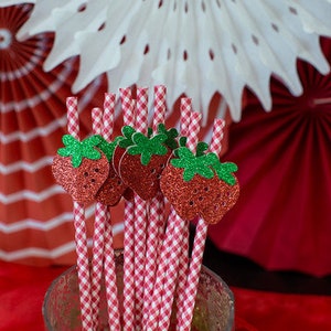 Pode incluir: Palhas de papel em xadrez vermelho e branco com detalhes de morango de glitter. As palhas est&atilde;o em um pote de vidro transparente.