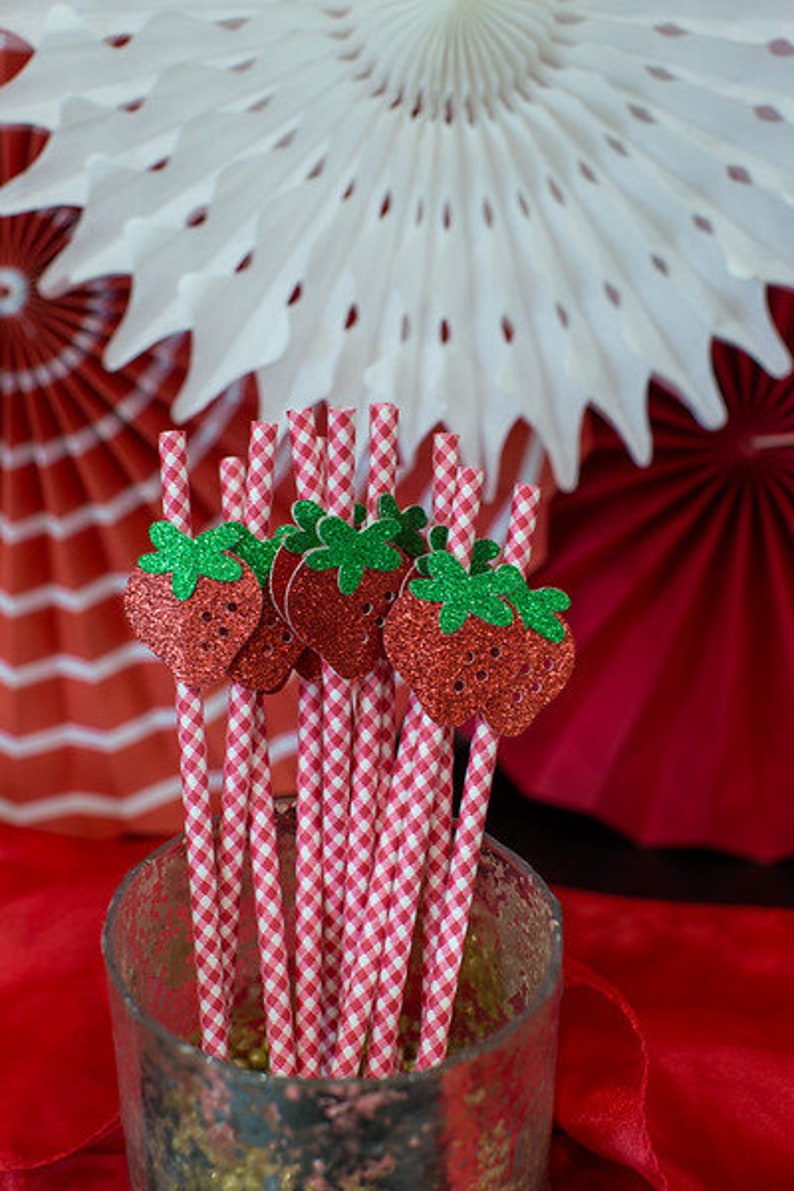Pode incluir: Palhas de papel em xadrez vermelho e branco com detalhes de morango de glitter. As palhas est&atilde;o em um pote de vidro transparente.