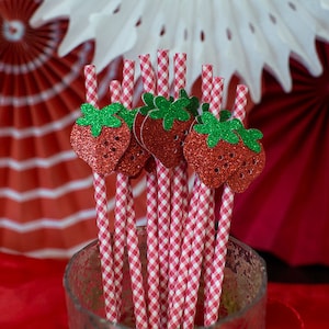 Pode incluir: Palhas de vichy vermelhas e brancas com topos de morango vermelho com glitter. As palhas est&atilde;o em um pote de vidro transparente.
