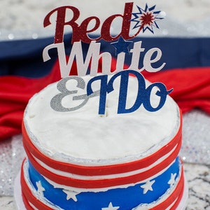 Pode incluir: Um bolo de casamento de dois andares decorado em vermelho, branco e azul com um topo que diz "Red White & Do".