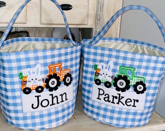 May include: Two blue and white gingham Easter baskets with personalized names, John and Parker. Each basket features an embroidered design of a bunny pulling a tractor.