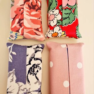 Pode incluir: Quatro capas para caixa de len&ccedil;os de papel feitas &agrave; m&atilde;o. Uma &eacute; rosa com bolinhas brancas, outra &eacute; cinza com estampa floral branca e preta, uma &eacute; vermelha com estampa floral verde e branca, e outra &eacute; azul claro com estampa floral branca e preta.