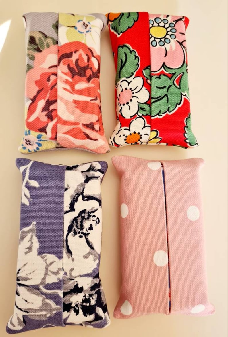 Pode incluir: Quatro capas para caixa de len&ccedil;os de papel feitas &agrave; m&atilde;o. Uma &eacute; rosa com bolinhas brancas, outra &eacute; cinza com estampa floral branca e preta, uma &eacute; vermelha com estampa floral verde e branca, e outra &eacute; azul claro com estampa floral branca e preta.
