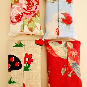 Pode incluir: Quatro capas de caixa de len&ccedil;os de tecido. Uma &eacute; floral com rosas cor-de-rosa e vermelhas sobre um fundo branco. Uma &eacute; azul com um padr&atilde;o floral branco e vermelho. Uma &eacute; bege com cogumelos vermelhos e pretos e flores vermelhas. Uma &eacute; vermelha com um p&aacute;ssaro branco e um padr&atilde;o floral.