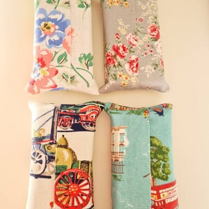 Pode incluir: Quatro capas de tecido para caixa de len&ccedil;os de papel. Uma &eacute; floral com flores rosa, azuis e verdes sobre um fundo branco. Outra &eacute; floral com flores rosa, vermelhas e amarelas sobre um fundo cinza. Uma &eacute; branca com um design de carro vintage vermelho, azul e verde. Outra &eacute; azul com um design de &ocirc;nibus de dois andares vermelho e uma &aacute;rvore verde.