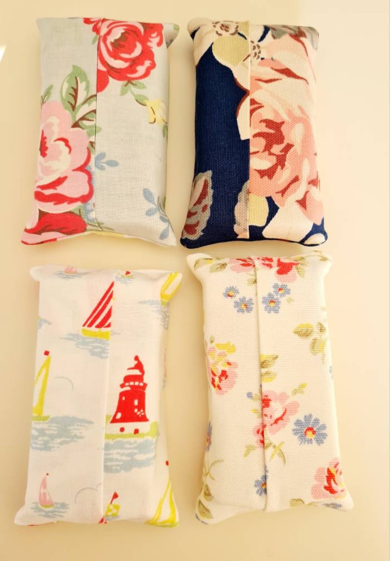 Pode incluir: Quatro capas de caixa de len&ccedil;os de tecido. Uma &eacute; azul com estampa floral branca e rosa, outra &eacute; branca com um farol vermelho e veleiros, uma &eacute; branca com estampa floral rosa e azul, e outra &eacute; branca com estampa floral rosa e verde.