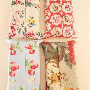 Pode incluir: Quatro capas de tecido para caixa de len&ccedil;os de papel. Uma &eacute; branca com estampa floral rosa e vermelha, outra &eacute; vermelha com estampa floral branca, uma &eacute; azul claro com estampa de morangos vermelhos e outra &eacute; bege com estampa floral vermelha, verde e amarela.